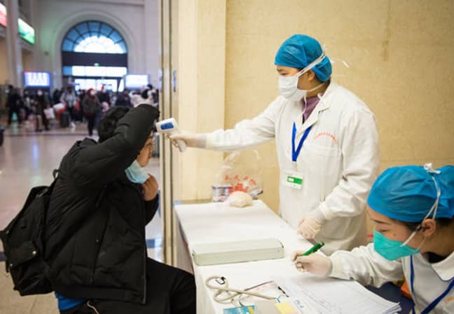 A medical worker takes a passenger's body temperature at Hankou Railway Station in Wuhan. Credit:  PA