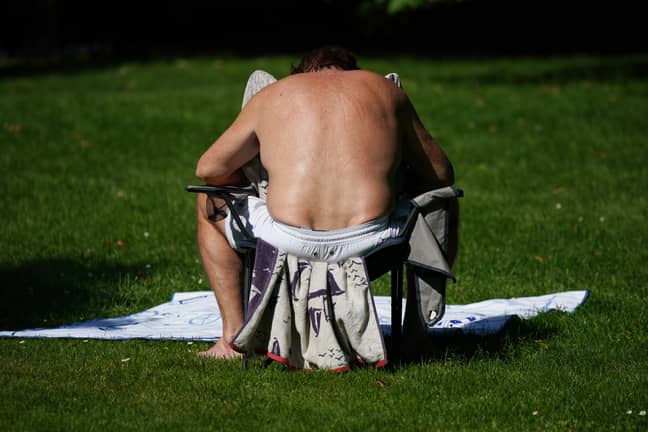 A man sunbathing in St James' Park, London. Credit: PA