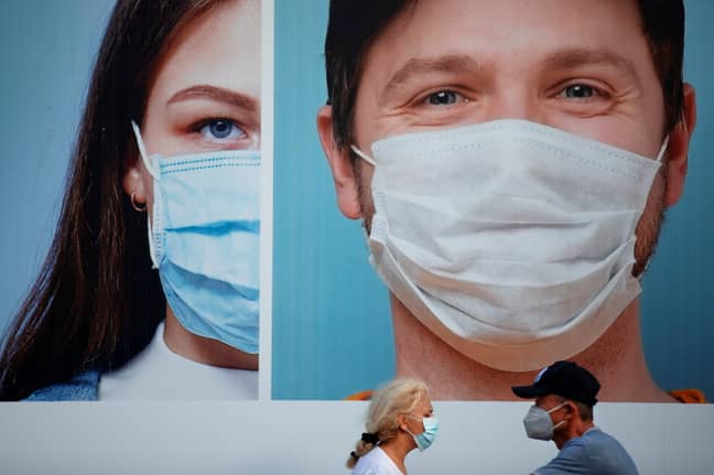Two people wearing masks in front of a billboard in Ramat Gan, near Tel Aviv, Israel. Credit: PA