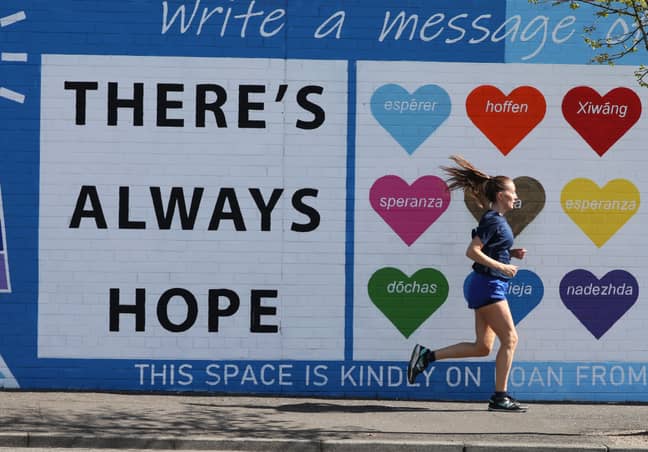 A woman runs past a mental health mural on the Falls road in west Belfast in April. Credit: PA