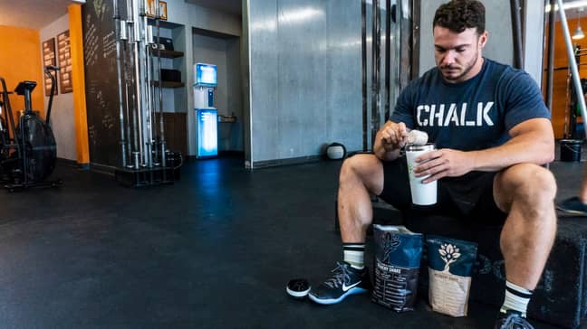 Guy prepares protein shake in the gym (Credit:Unsplash/lyfefuel)