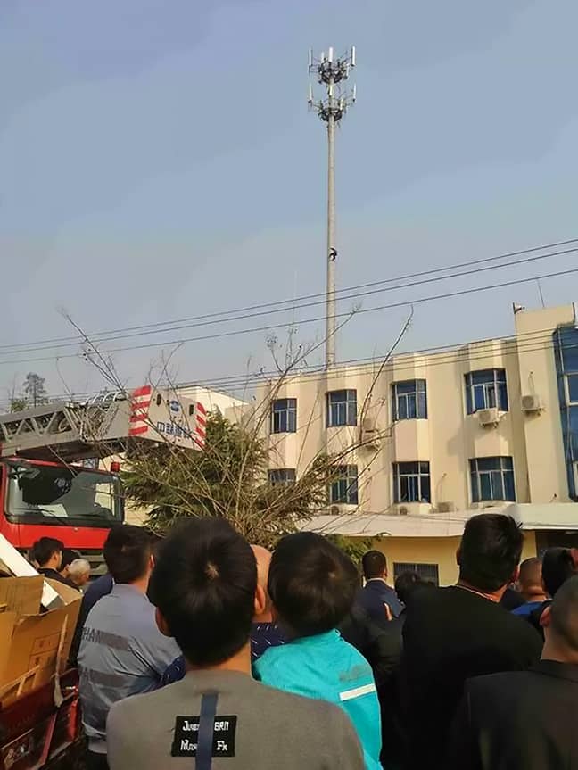 People watched on as the man was stuck up the phone mast. Credit: Asia Wire