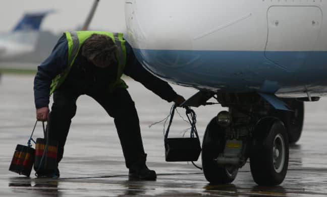Stock photo of a member of airport staff attending to a plane. Credit: PA