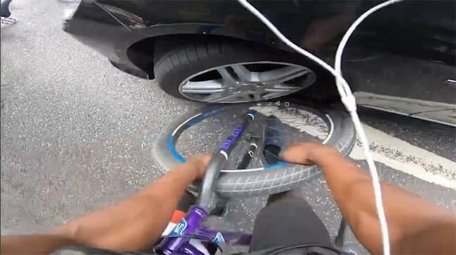 The cyclist's bike was trapped under the front wheel of the car. Credit: YouTube
