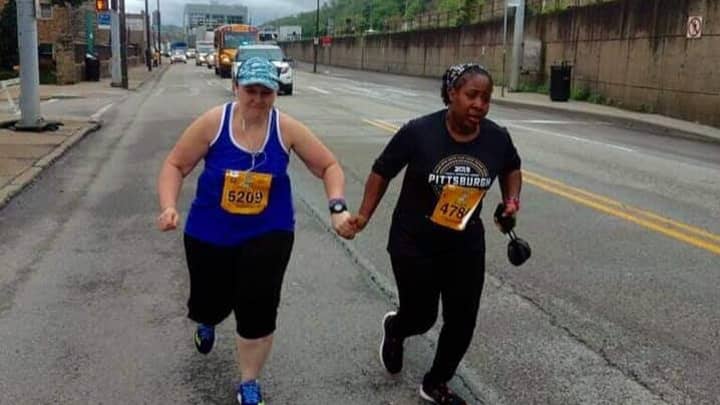 ​Marathon Runners Cross Finish Line Holding Hands As Final Competitors