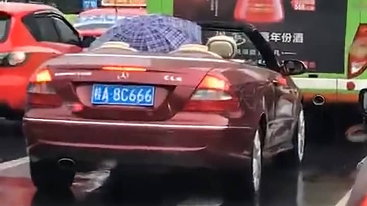 Man Uses Umbrella To Escape The Rain In His Convertible Mercedes